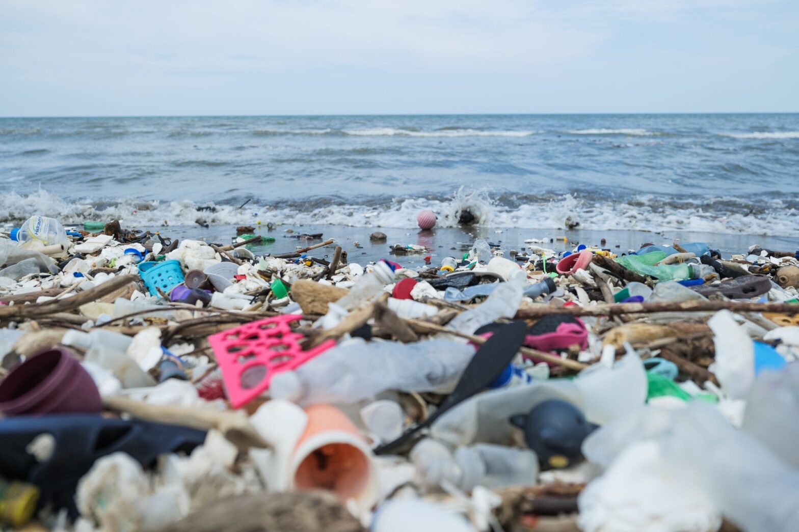 A sea turtle swimming near floating plastic debris in the ocean, highlighting the impact of pollution on marine life.