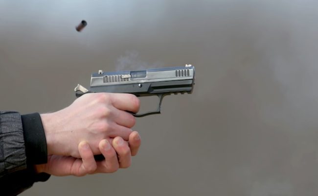 pistol-shooting-with-two-hands-shells-emanating-from-shutter-blue-smoke_402759-1460